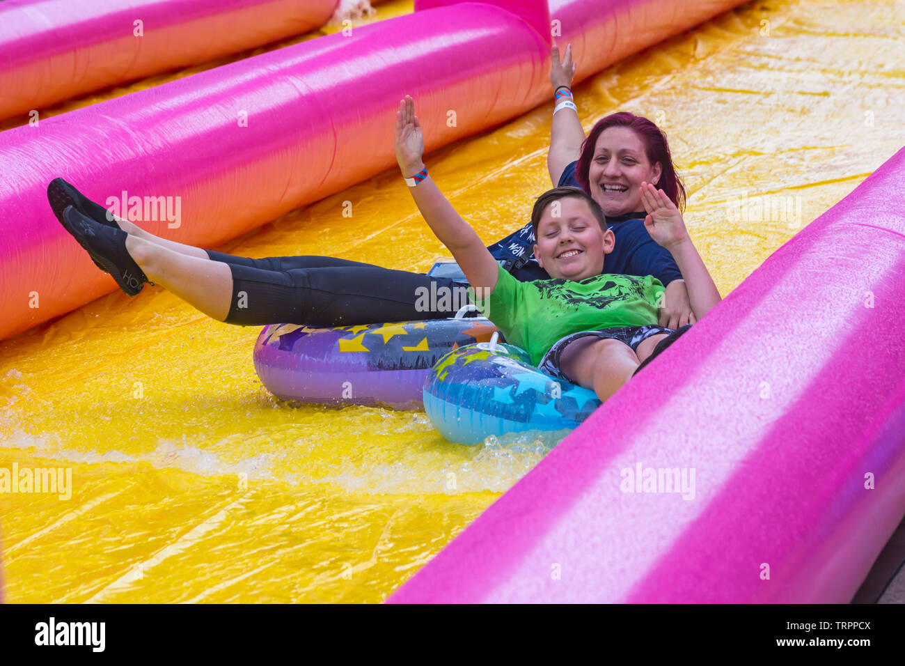 Woman and boy sur anneaux gonflables s'amusant sur le toboggan géant, toboggan, à Bournemouth, Dorset UK en Juin Banque D'Images