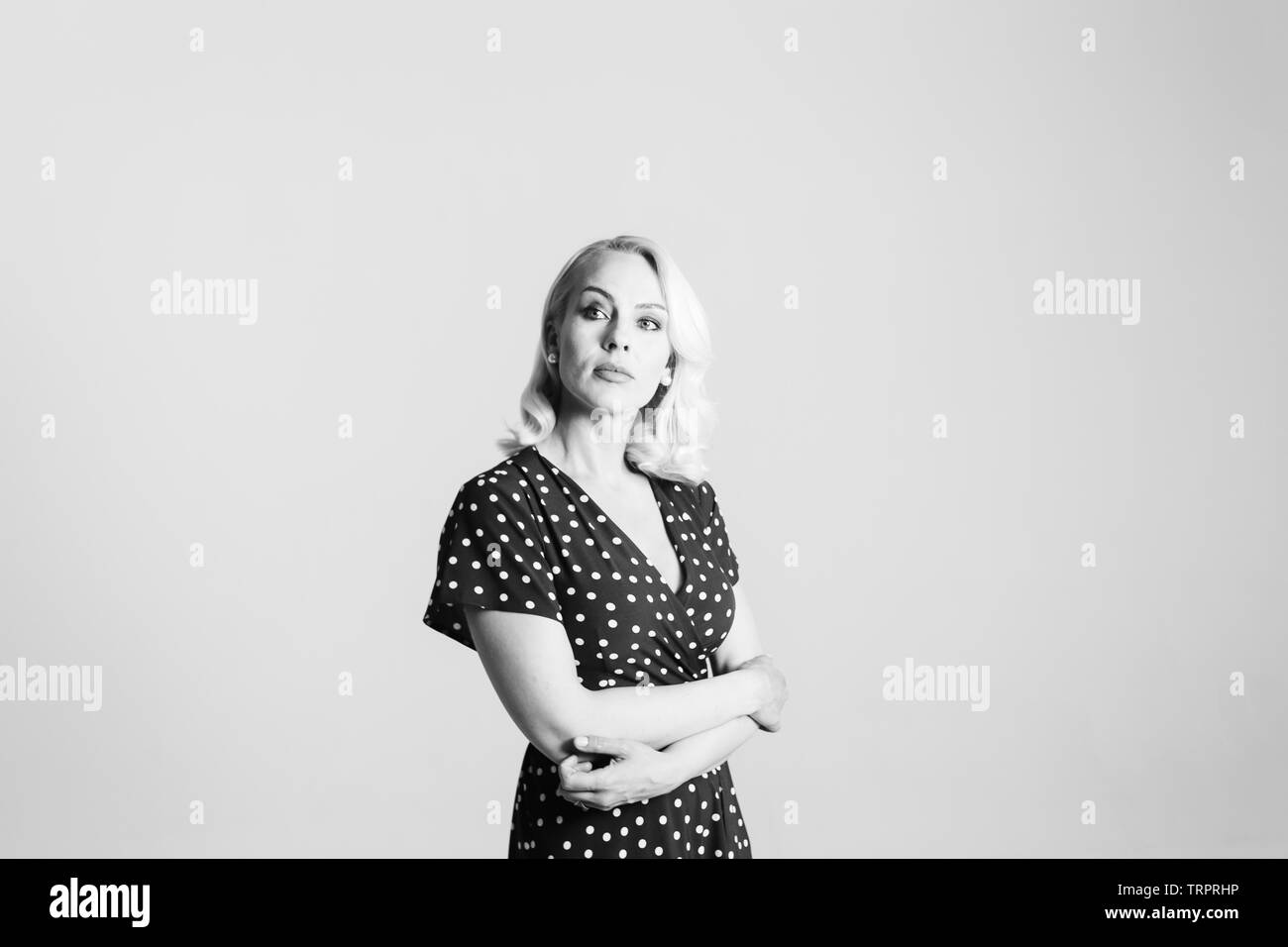 Portrait de studio de belle blonde woman in a black dress contre fond uni blanc Banque D'Images