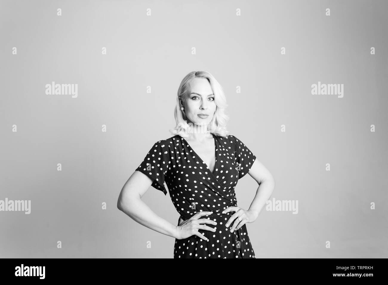 Portrait de studio de belle blonde woman in a black dress contre fond uni blanc Banque D'Images