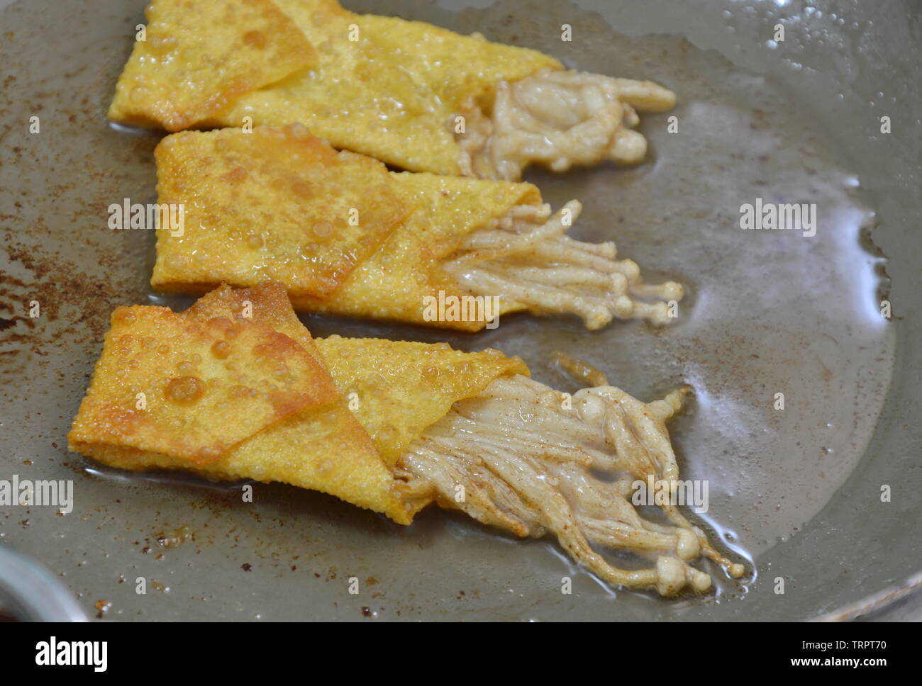 Champignons frits aiguille enrouler dans la farine dumpling cuisson sur pan Banque D'Images