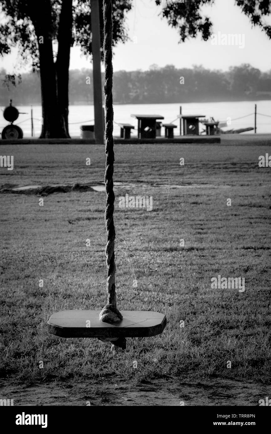 Une sombre et mystérieux artisanal en bois isolé siège pour un arbre par une corde pend swing dans parc sur les rives de la rivière Mississippi Banque D'Images
