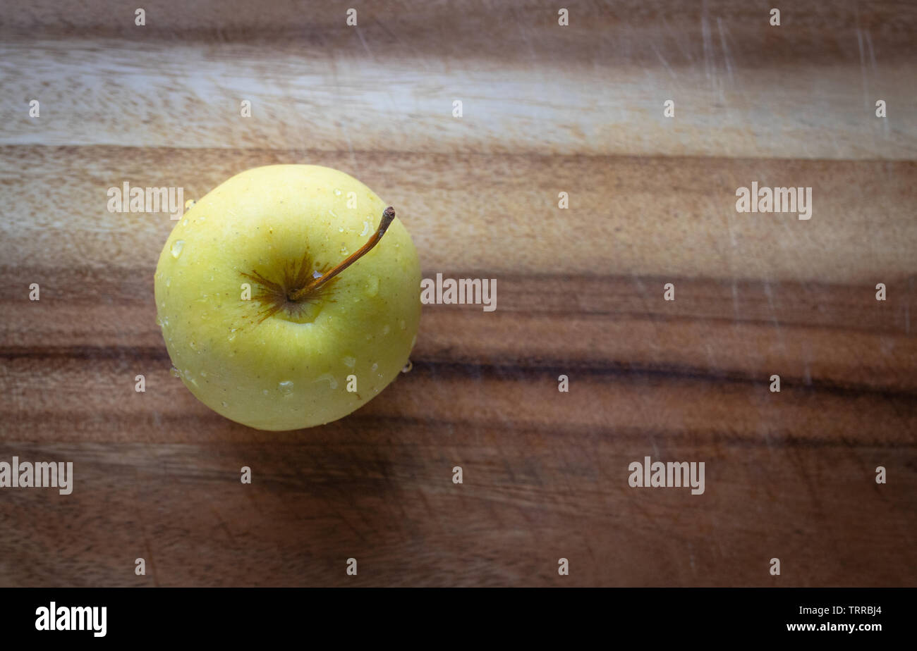 Une pomme Golden Delicious sur une planche en bois en format horizontal. Banque D'Images