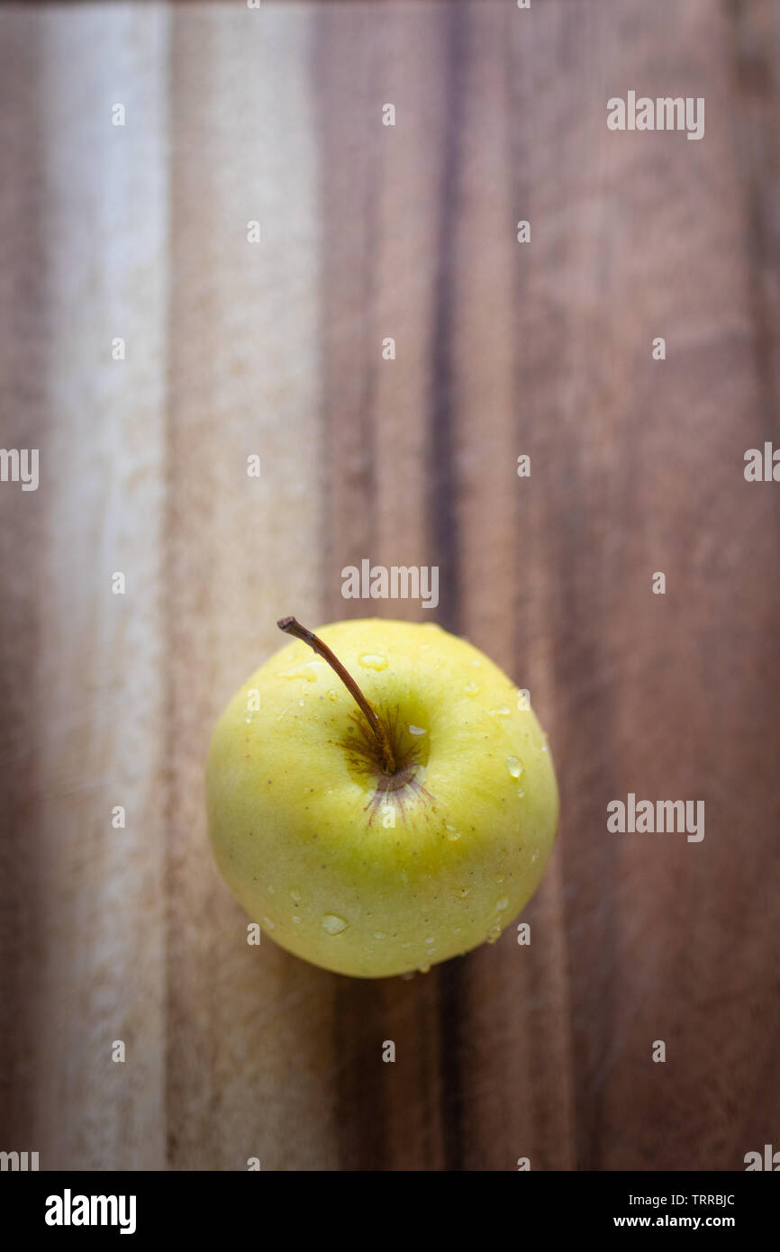 Pomme Golden Delicious sur une planche, en format vertical. Banque D'Images