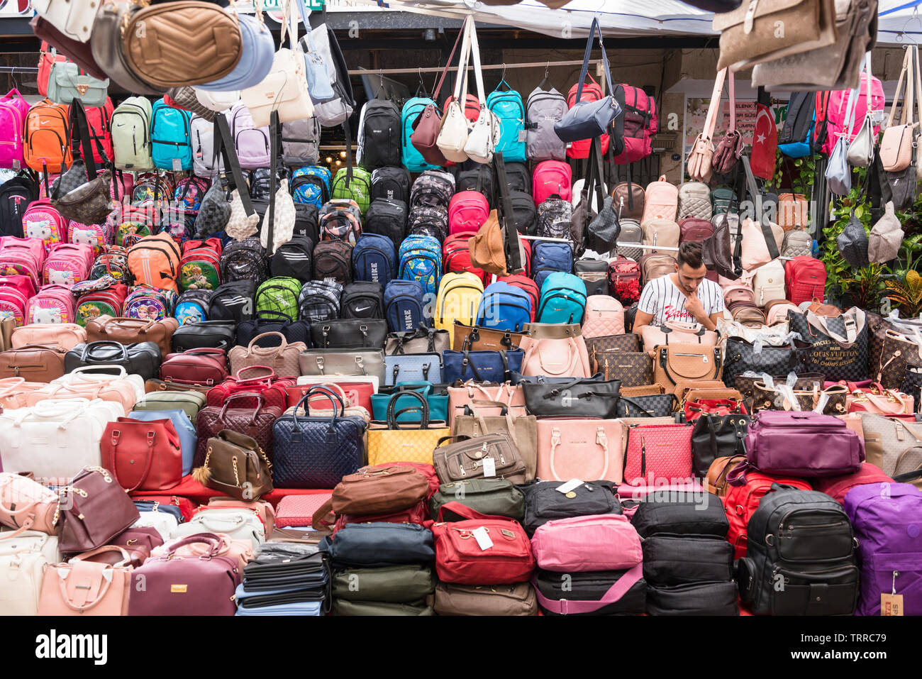 Exposant entouré de sacs et bagages, apparemment faite par des marques bien connues, au marché le samedi, Marché, aka Berivan Selcuk, Turquie. Banque D'Images