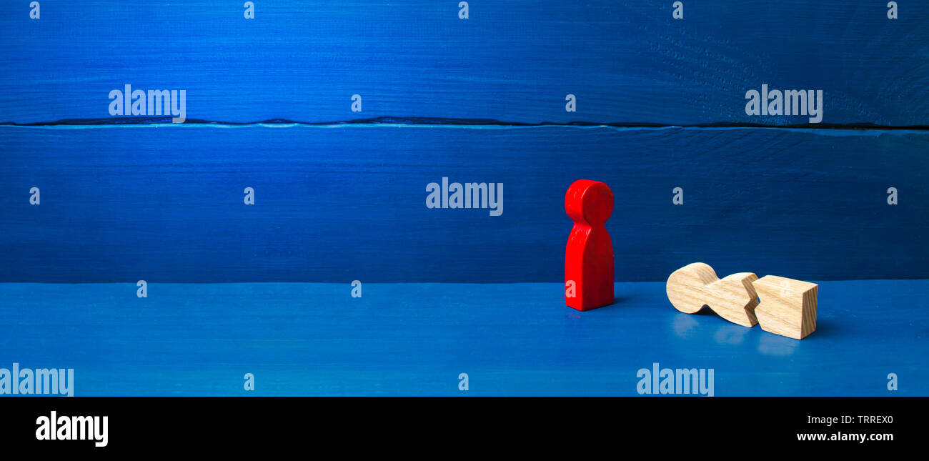 Une figurine d'un homme rouge se tient sur un split tombé l'homme. Le concept de l'aide mutuelle, les premiers soins. La protection sociale et de l'attention. Physique et psychologique Banque D'Images