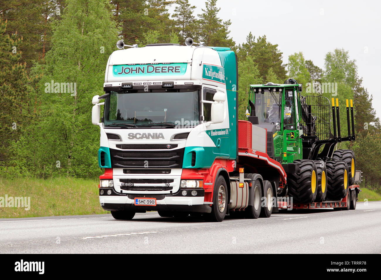 Raasepori, Finlande. Le 24 mai 2019. Scania R560 colorés semi-remorque de Kuljetusliike J'Huohvanainen Oy parcours nouveau John Deere forestry machinery sur route Banque D'Images