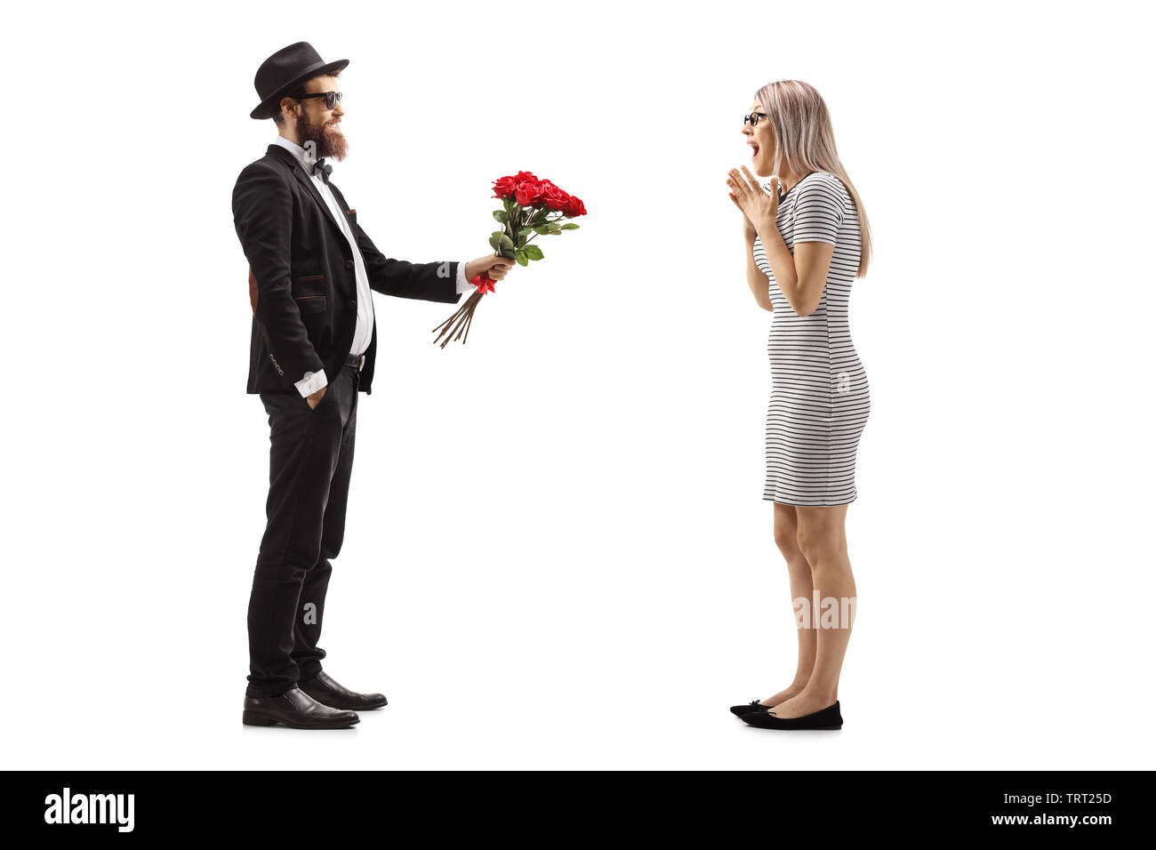 Profil de toute la longueur d'un homme en costume donnant un bouquet de roses rouges à une femme surprise isolé sur fond blanc Banque D'Images