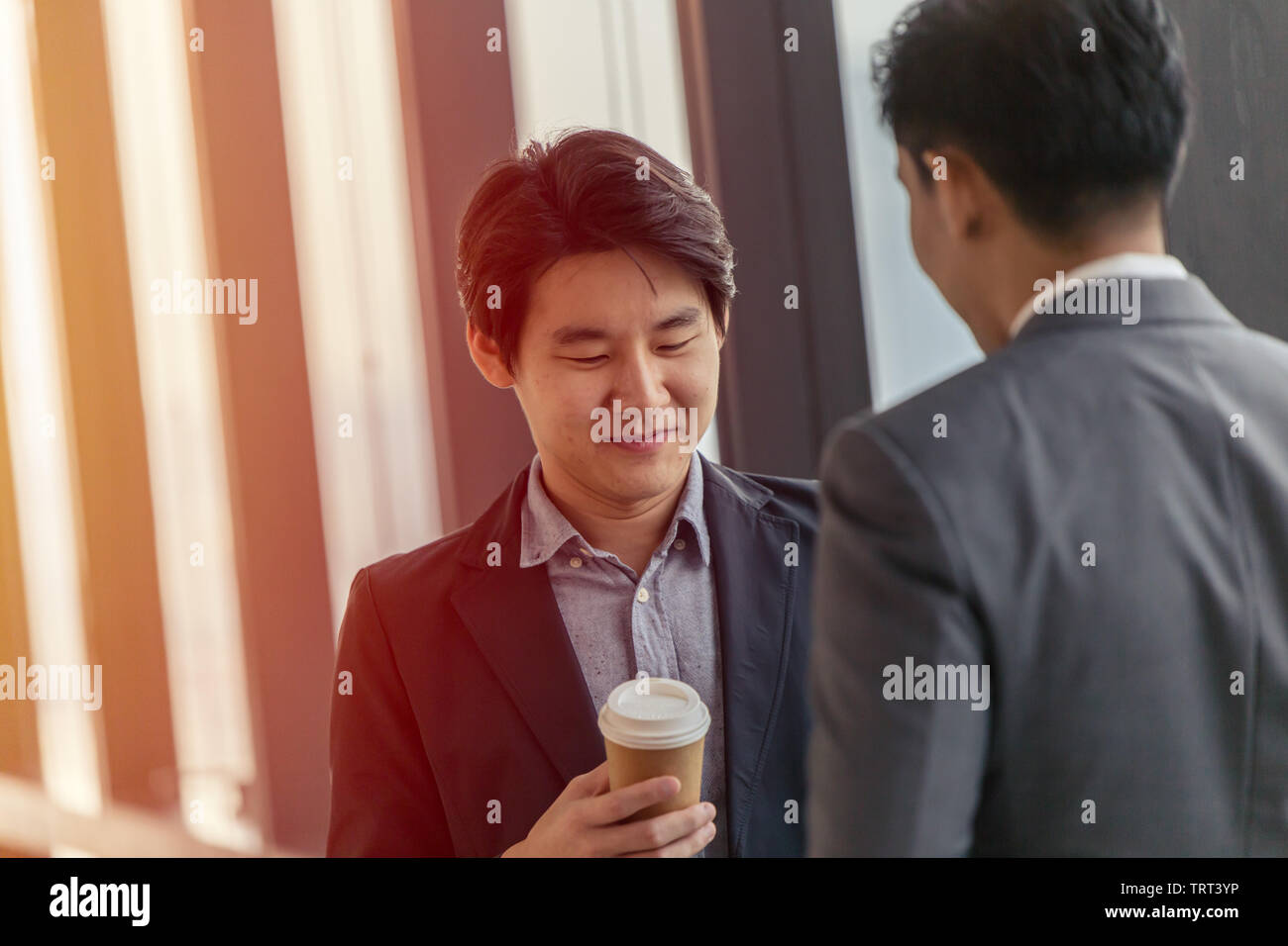 Jeune homme d'aspect professionnel leader asiatique parler ensemble dans le bureau avec la tasse de café chaud dans la main Banque D'Images