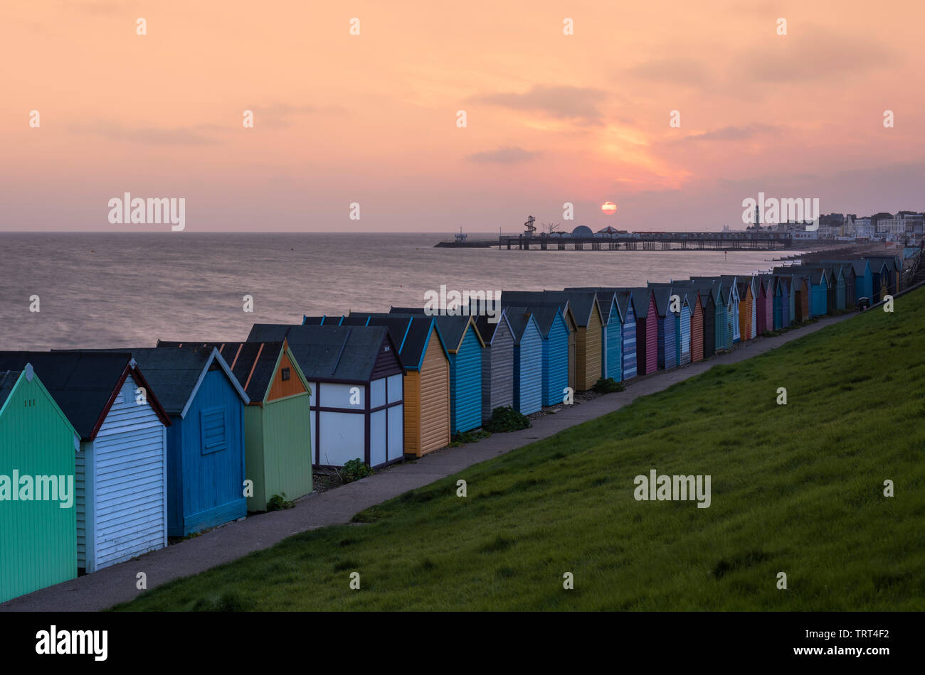 Cabines colorées sur Herne Bay seafront comme le soleil se lève sur le quai historique. Banque D'Images