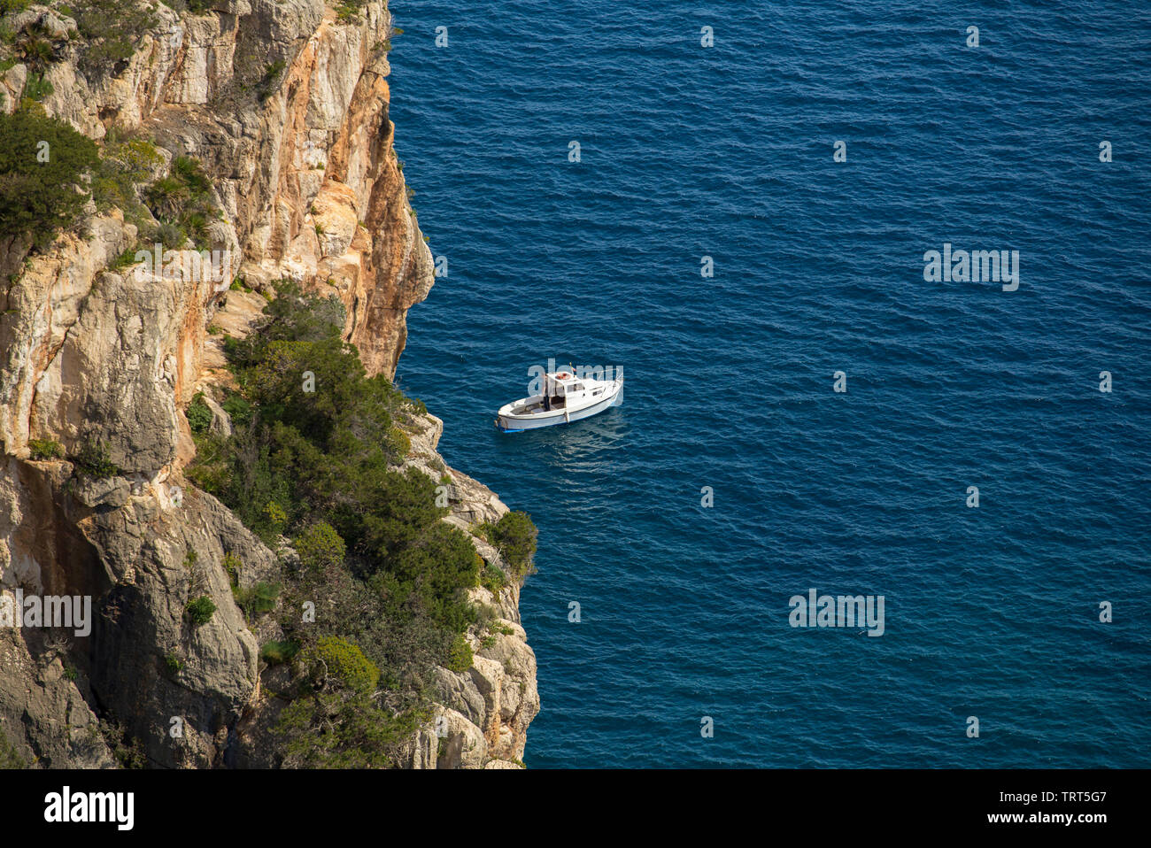 Vue aérienne de petit bateau dans le bleu de la mer et les falaises de l'arrière-plan. Italie Sardaigne Banque D'Images