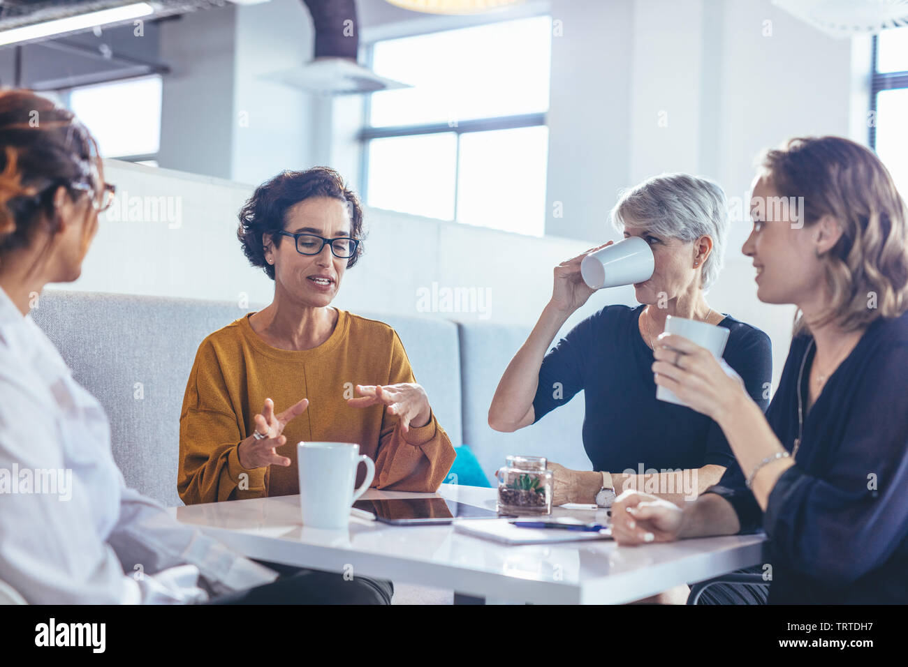 Groupe de quatre femmes d'affaires ayant une discussion en bureau. Professionnels féminins assis autour d'une table et de remue-méninges au nouveau plan d'affaires. Banque D'Images