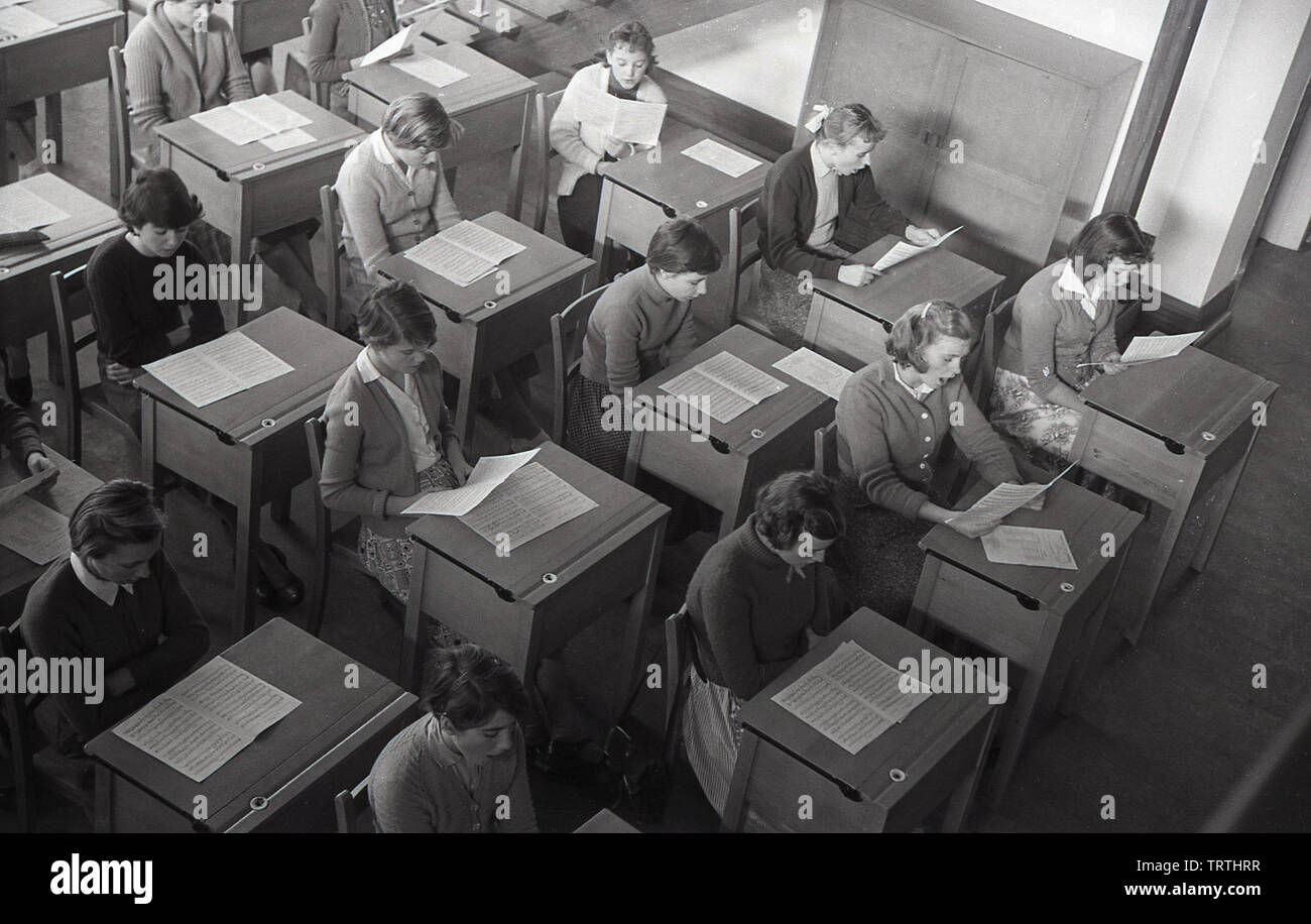 Années 1950, historique, vue aérienne d'une leçon de musique ayant lieu à une ville secondaire, montrant les écolières assis à un bureau avec leurs partitions, England, UK. Banque D'Images