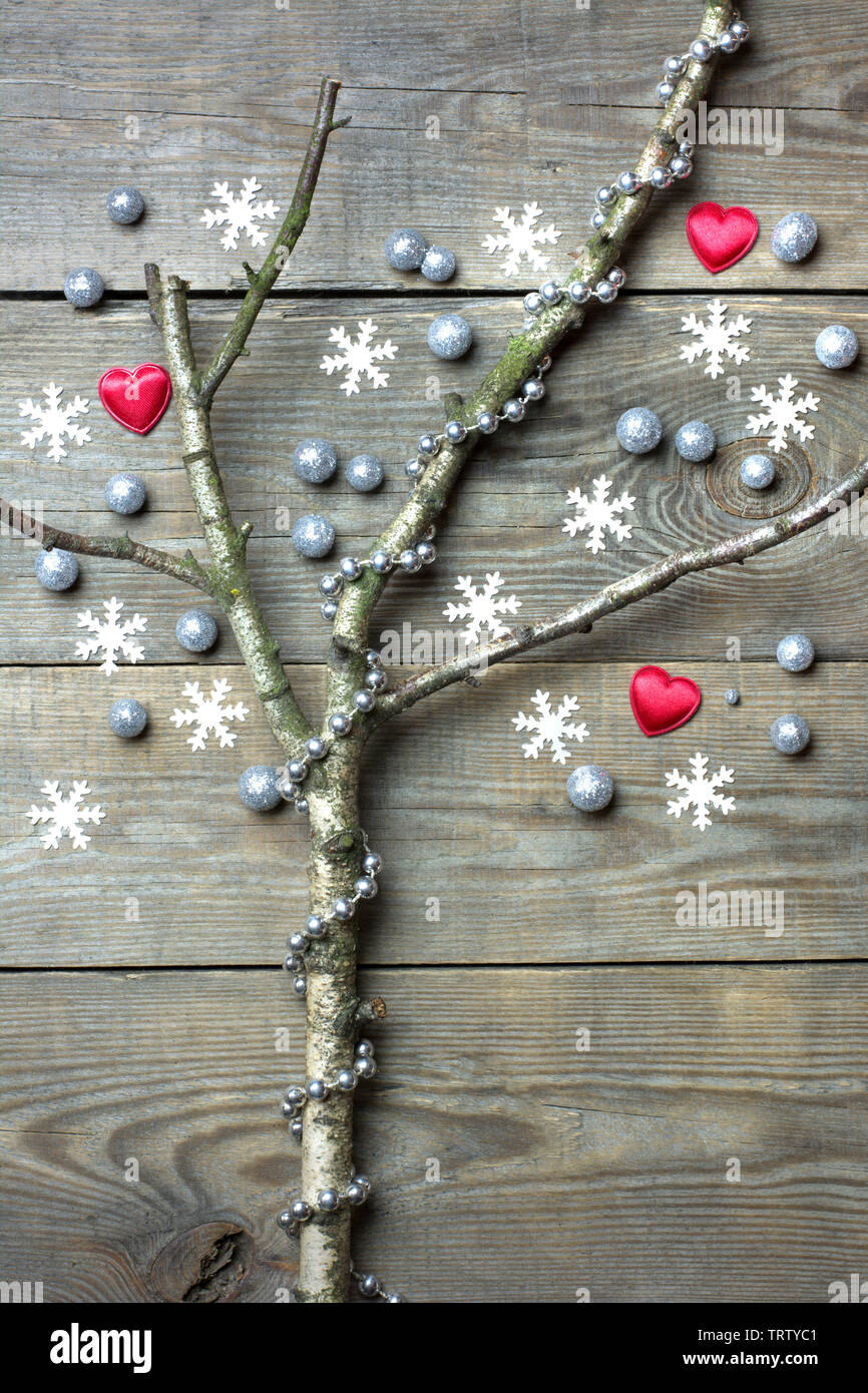 Concept d'arbre de Noël avec des branches d'arbres sans feuilles, flocons de neige, coeur rouge, d'argent et les globules de chaîne de perles sur fond de bois Banque D'Images