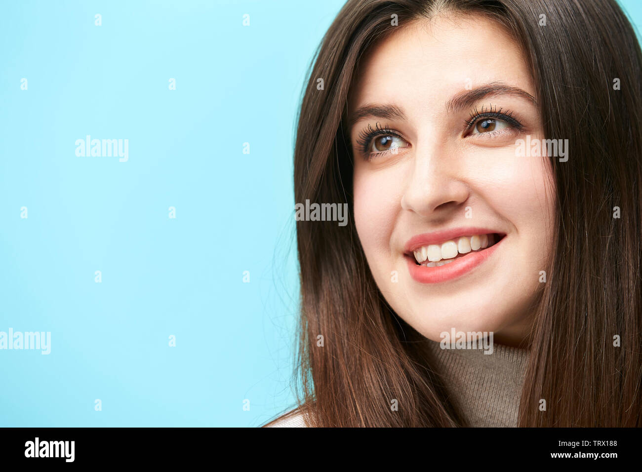 Head shot portrait of a young woman isolé sur fond bleu Banque D'Images