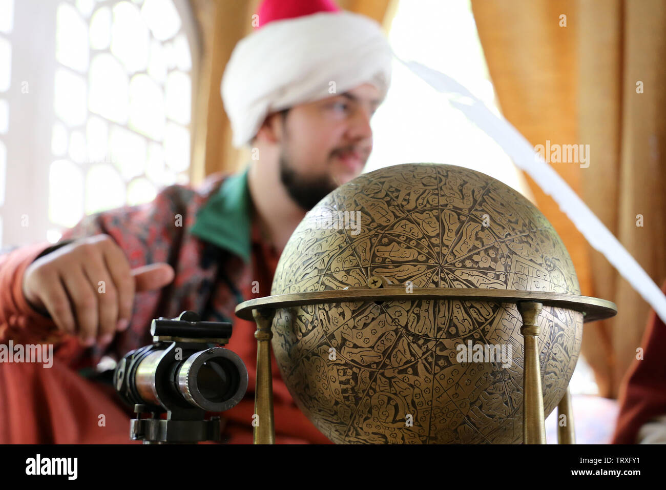 Scientifique médiévale en turban assis avec un ancien monde et spyglass pendant le temps du festival historique de Moscou et les époques. La vie en Empire Ottoman Banque D'Images