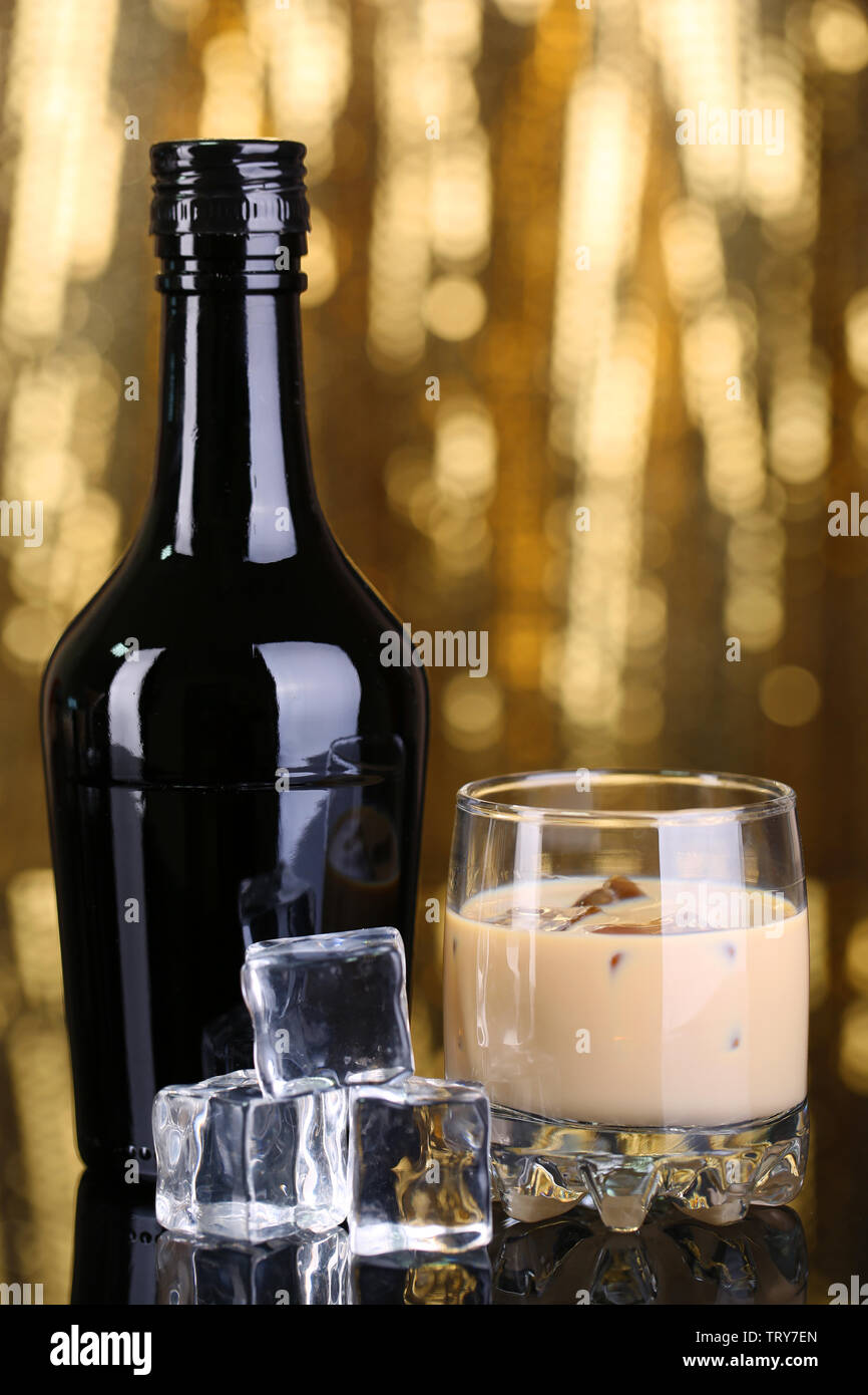 Liqueur Baileys en bouteille et verre sur fond doré Banque D'Images