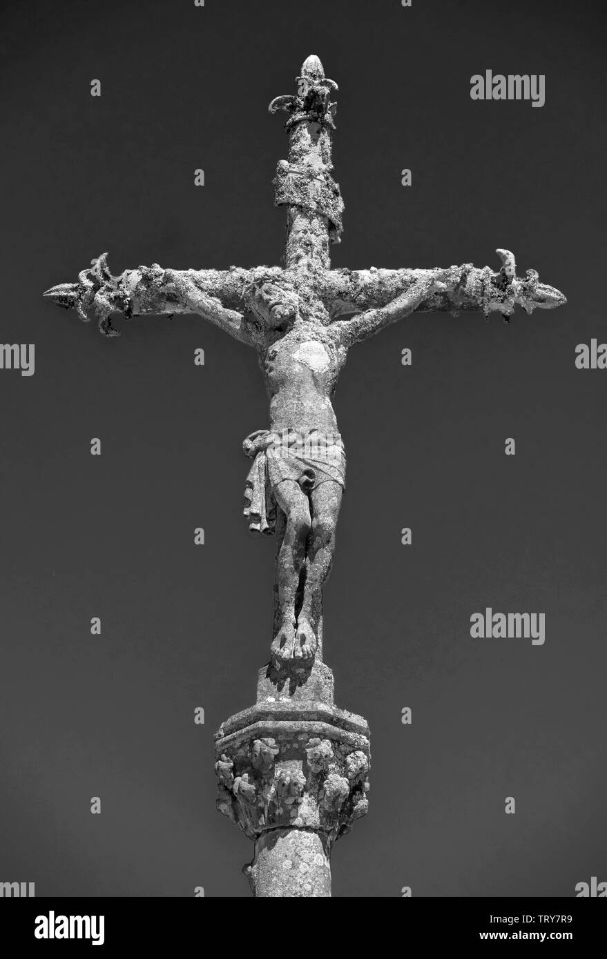 Photo monochrome d'une statue de pierre du Christ sur la croix à un cimetière dans la Feuillée, Bretagne, France. Banque D'Images
