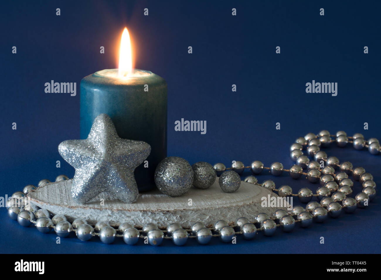 Composition de noël bleu et argent avec bougie allumée, glitter, globules et la chaîne de perles sur fond bleu foncé - espace texte Banque D'Images
