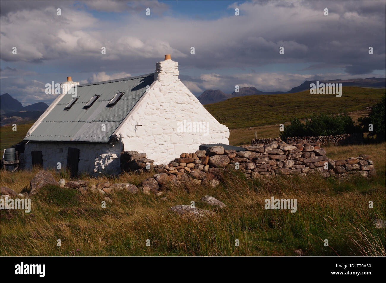 Vue d'un crofters à cottage sur la péninsule de Coigach Ecosse, avec des montagnes en arrière-plan et un mur en pierre sèche dans l'avant-plan Banque D'Images