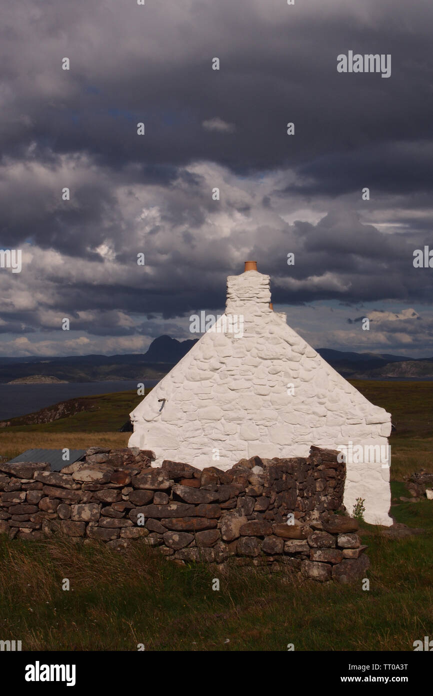 Une vue sur le pignon d'un crofters à chalet sur l'Pninsula Coigach Ecosse, avec les montagnes et la mer en arrière-plan et un mur en pierre sèche Banque D'Images
