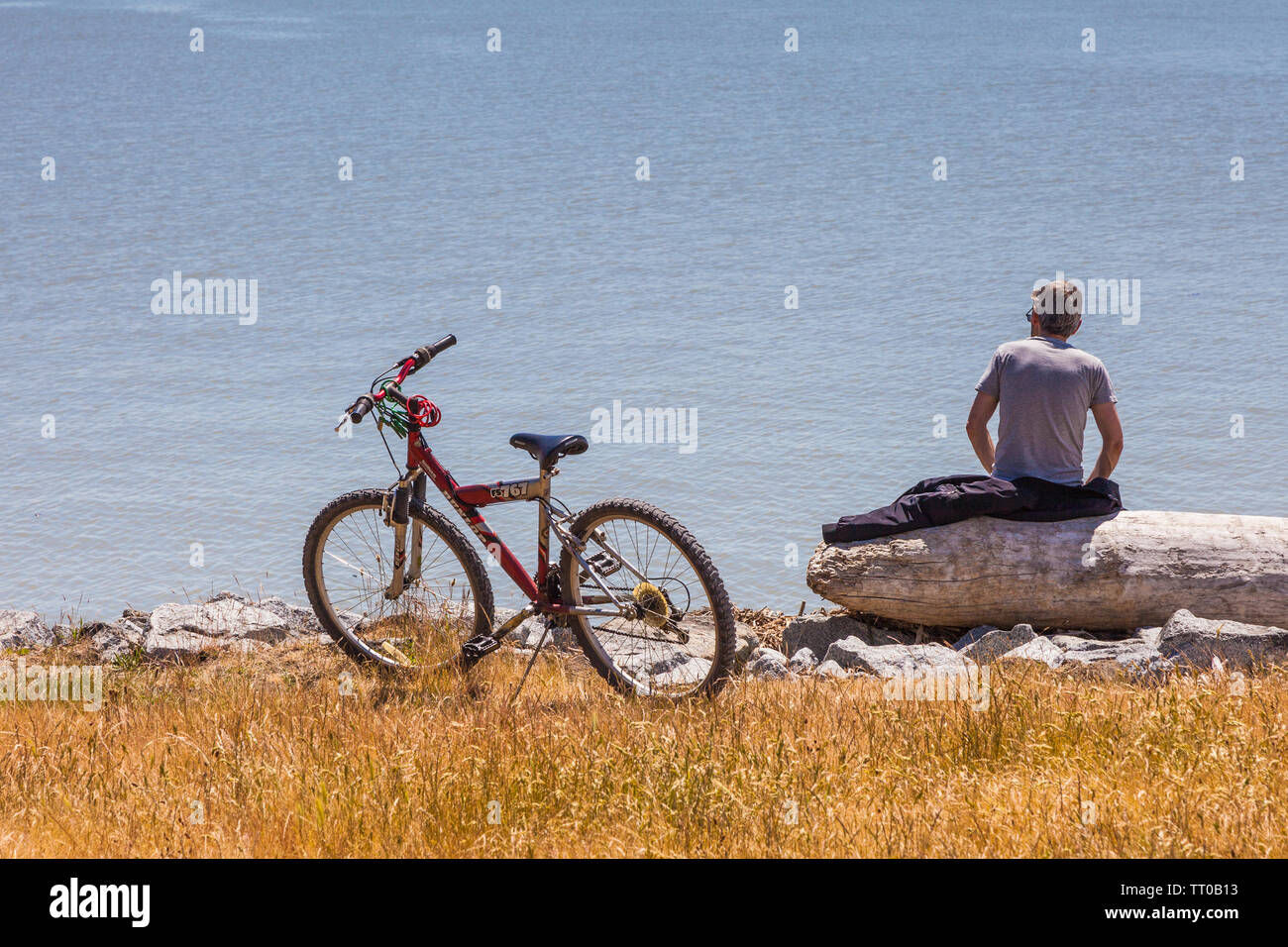 Bicycle Rider reposant sur un enregistrement par l'océan à Steveston en Colombie-Britannique Banque D'Images