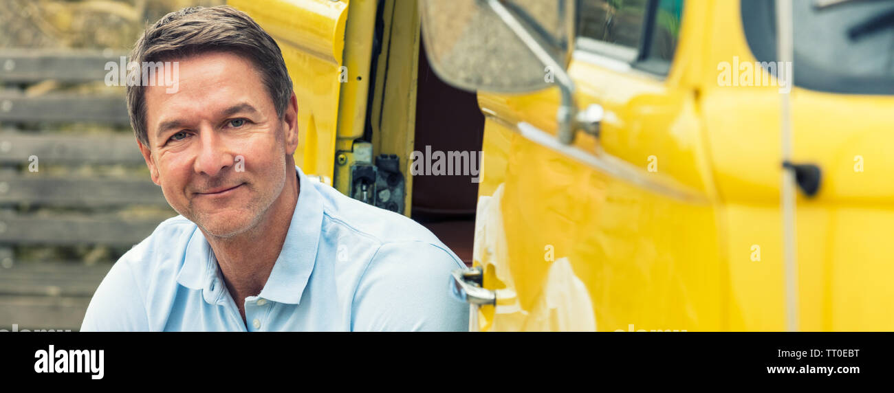 Bannière web panoramique portrait d'une belle réussite, et happy middle aged man homme vêtu d'un polo bleu, sitting smiling dans le doorw Banque D'Images
