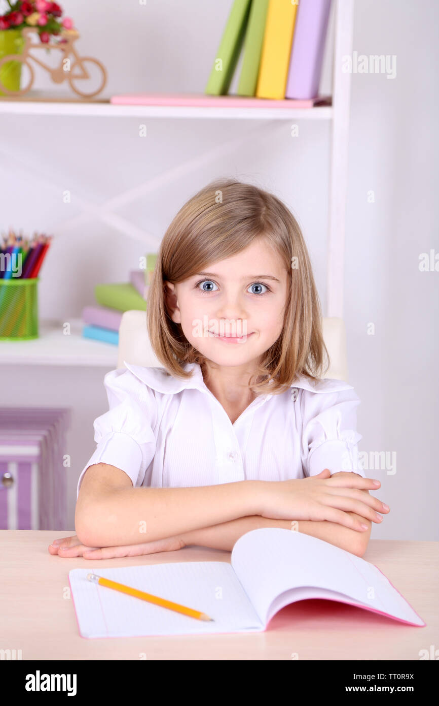 Petite fille assise au bureau dans la chambre Banque D'Images