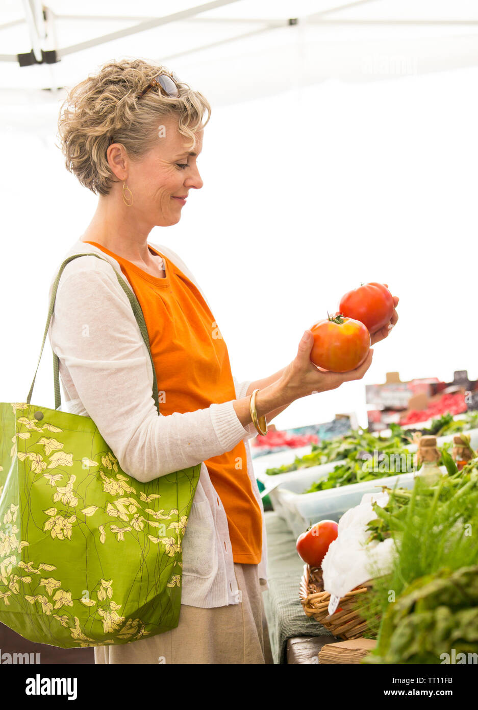 Belle, heureuse, saine middle aged woman shopping pour produits frais biologiques tomates à farmers market Banque D'Images
