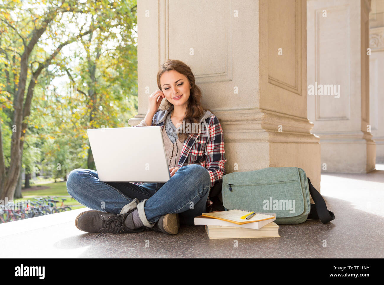 Jeune femme female college university student avec écouteurs écouteurs d'étudier à l'aide d'un ordinateur portable Banque D'Images
