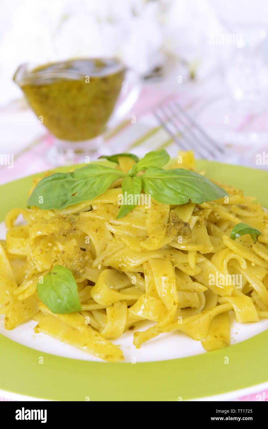 Délicieux plats de pâtes au pesto sur la plaque sur la table sur un fond clair Banque D'Images