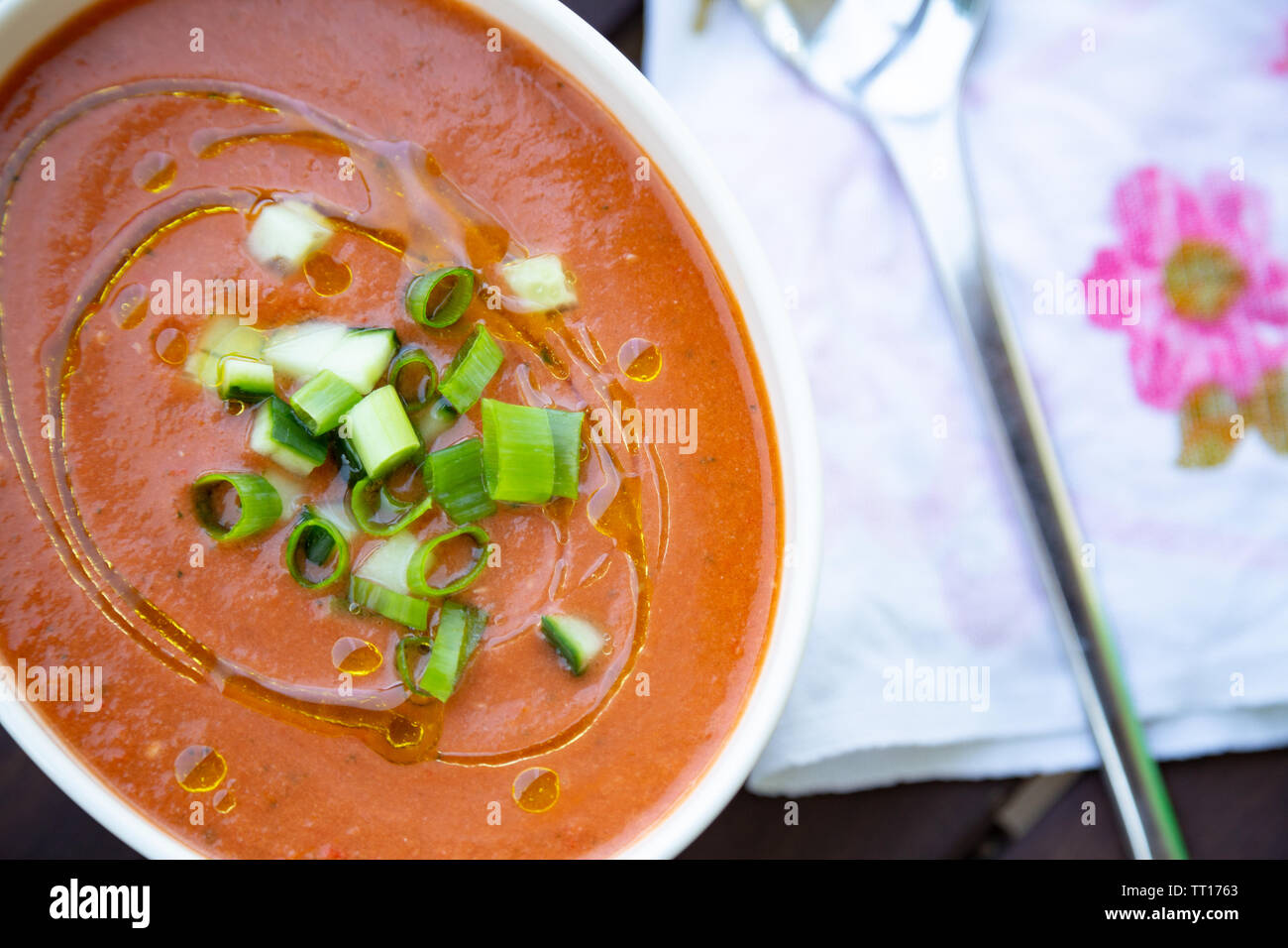 Gaspacho vegan traditionnel espagnol présenté sur une table en bois avec l'huile d'olive et huile de concombre et d'oignon vert Banque D'Images