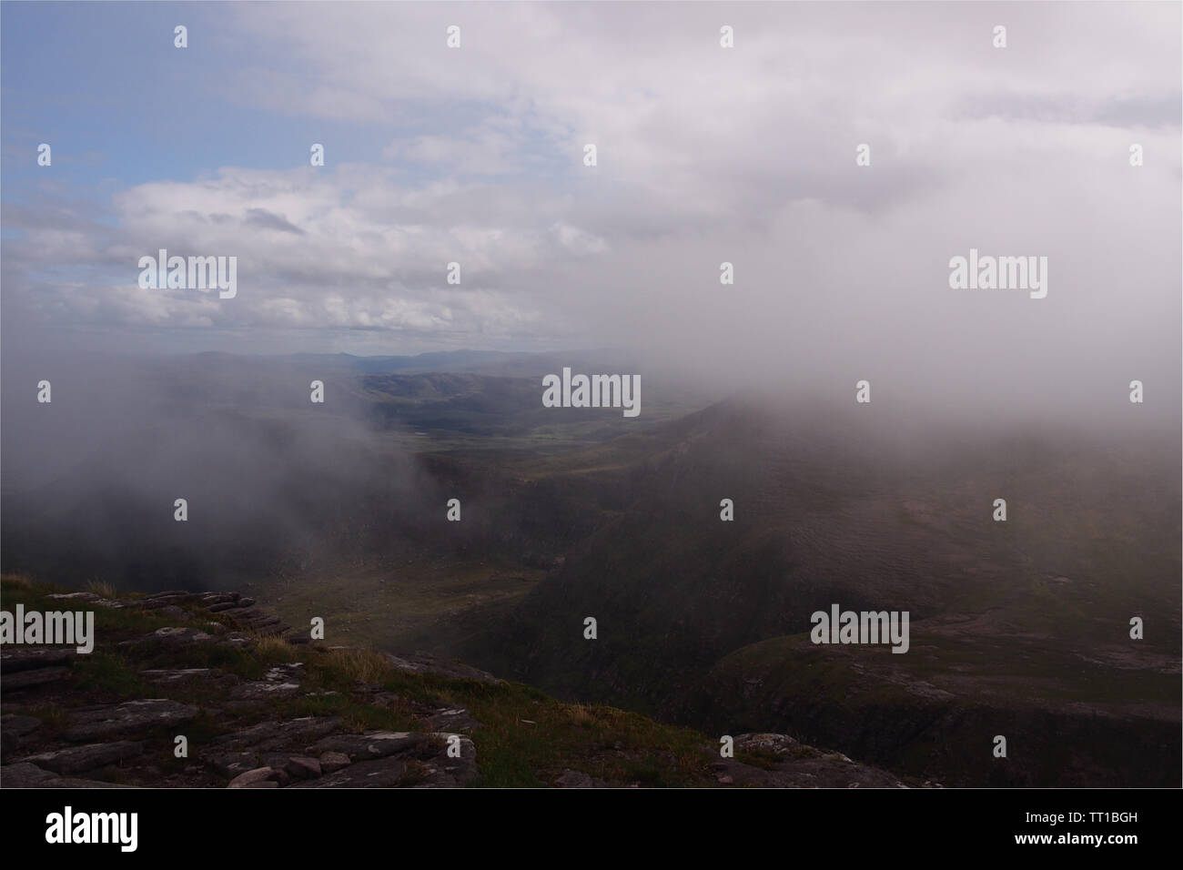Une vue de la montagne, dans la péninsule de Coigach, Ecosse avec passant filandreux nuages masquant une partie de la vue et des parcelles de ciel bleu Banque D'Images