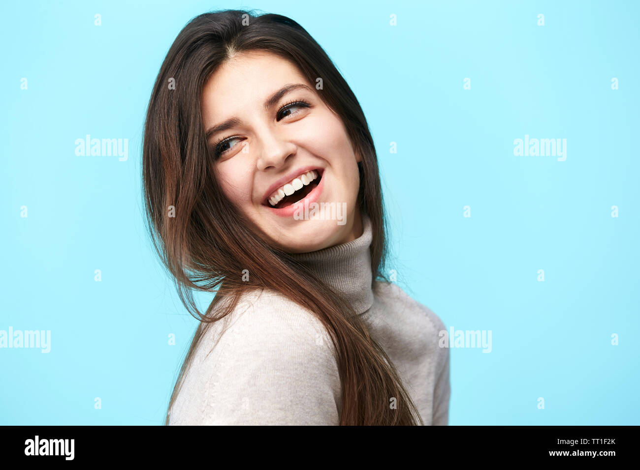 Portrait of a young woman with long hair, heureux et souriants, isolé sur fond bleu Banque D'Images