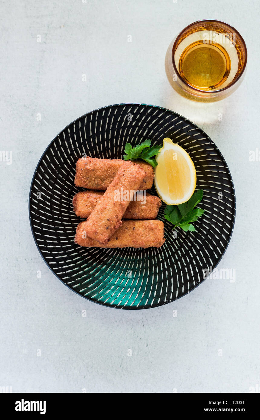 Entree de la polenta wedges empilés sur une plaque noire avec un citron et verre de bière Banque D'Images