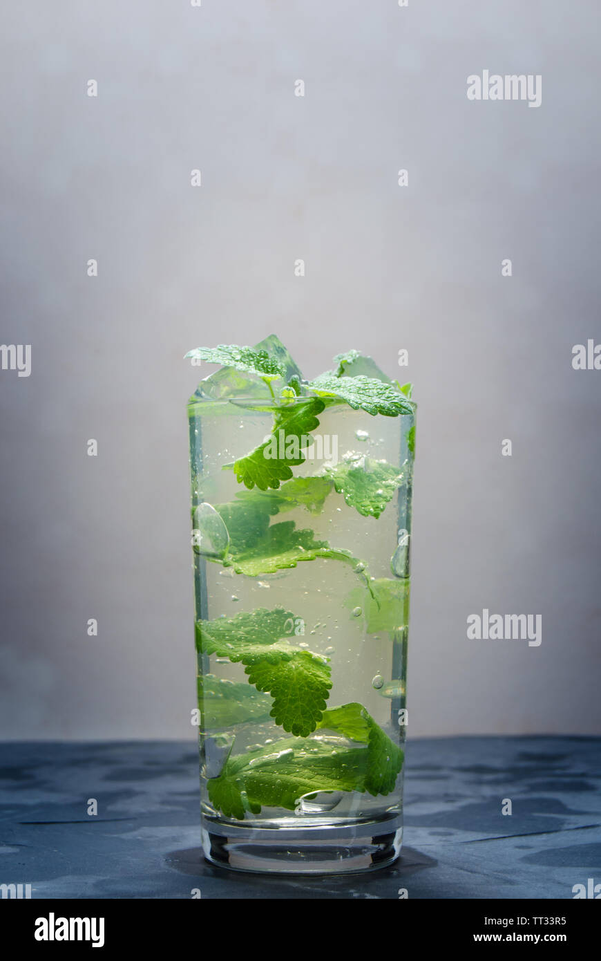 L'eau fraîche dans un verre de glace et pétales menthe.Soft drink, avec le vignetage. Banque D'Images