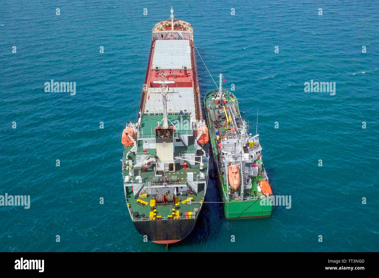 Le ravitaillement en mer - petits produits d'huile alimentant un grand navire vraquier, de l'image aérienne. Banque D'Images