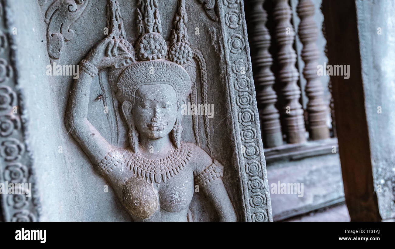 Détail d'une sculpture antique avec un corridor flou en arrière-plan dans la diminution de la perspective dans le magnifique temple Bayon - un Khmer décoration Banque D'Images