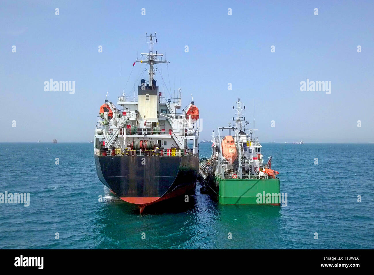 Le ravitaillement en mer - petits produits d'huile alimentant un grand navire vraquier, de l'image aérienne. Banque D'Images