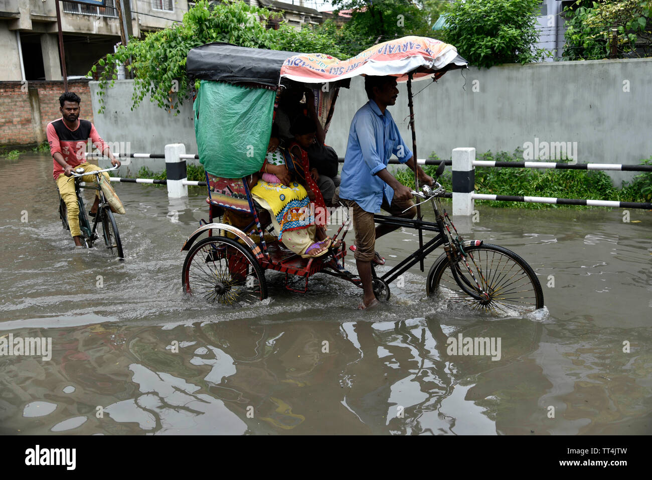 Guwahati, Assam, Inde. 14 juin, 2019. Les banlieusards patauger dans une rue gorgé d'eau après de fortes pluies dans la région de Guwahati, Assam, Inde le vendredi, Juin 14, 2019. Crédit : David Talukdar Alamy Live News Banque D'Images