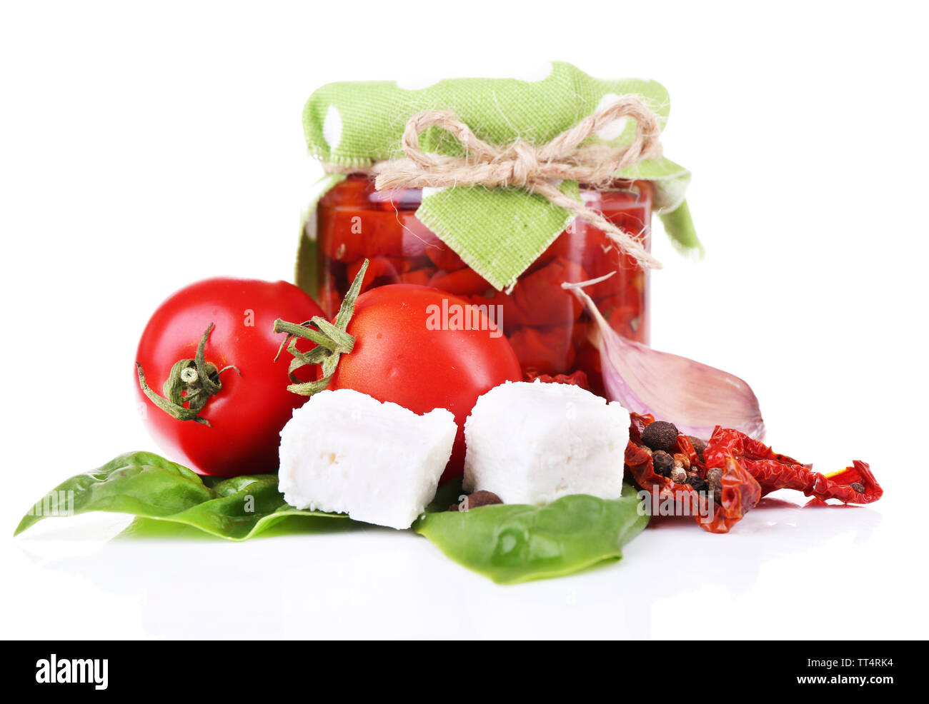 Des tomates séchées dans un bocal en verre, fromage feta et basilic feuilles isolées sur fond blanc Banque D'Images