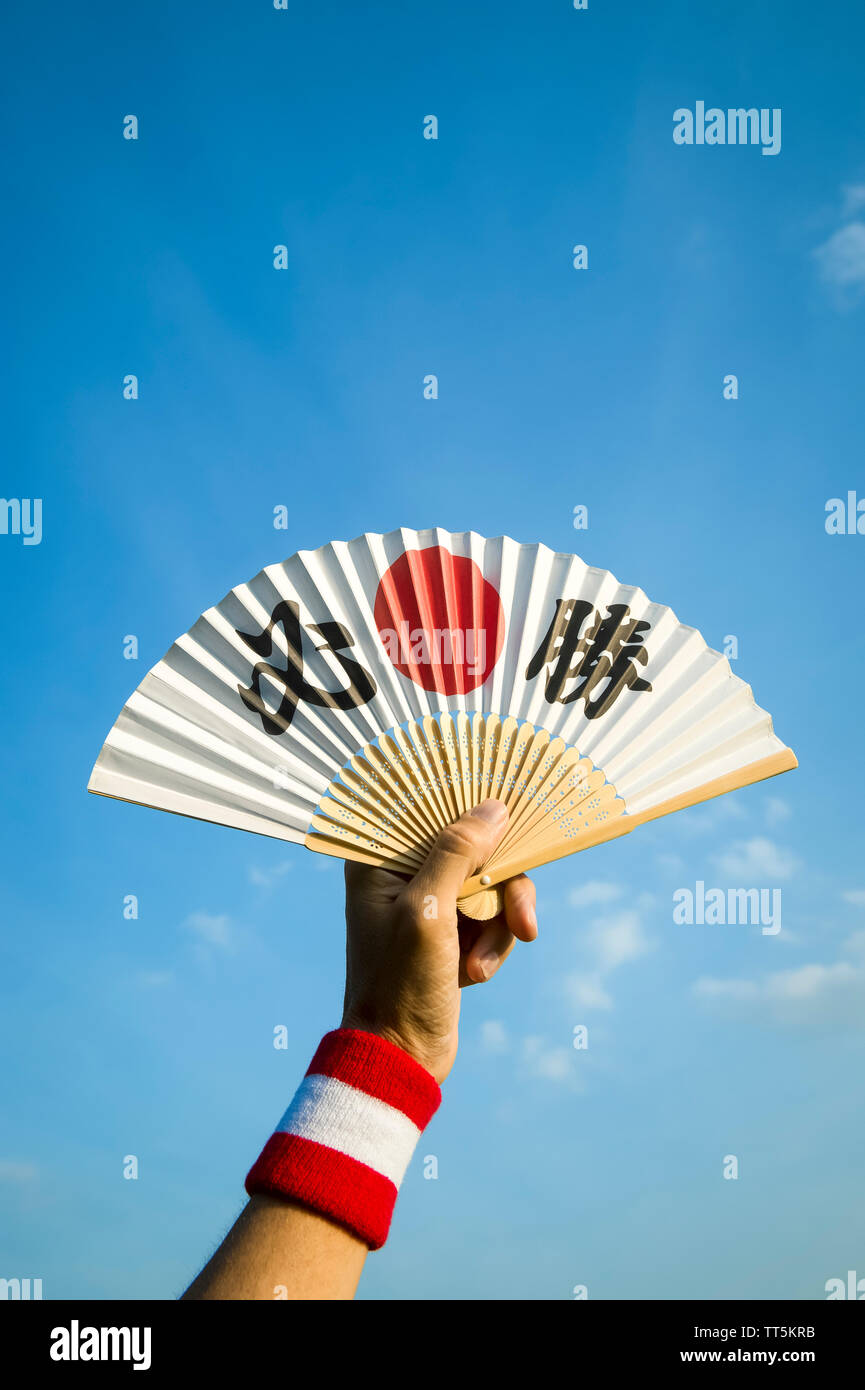 De la main tenant un supporteur sport japonais fan décoré de caractères  kanji énonçant hissho (traduction anglaise : certaines victoire) dans le  ciel bleu Photo Stock - Alamy