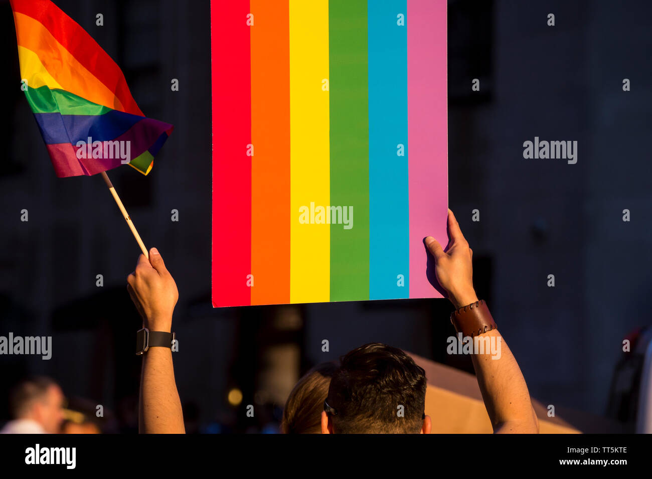 Vue d'arcs-en-ciel colorés drapeaux et signes détenus dans un méconnaissable foule à une gay pride parade dans la ville Banque D'Images