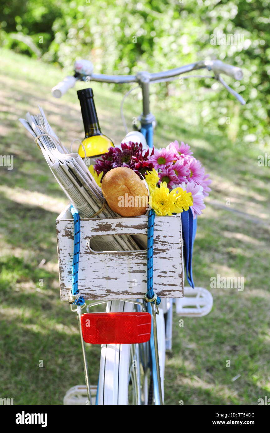 Location avec des fleurs, du pain et une bouteille de vin dans la boîte en bois sur fond d'herbe Banque D'Images