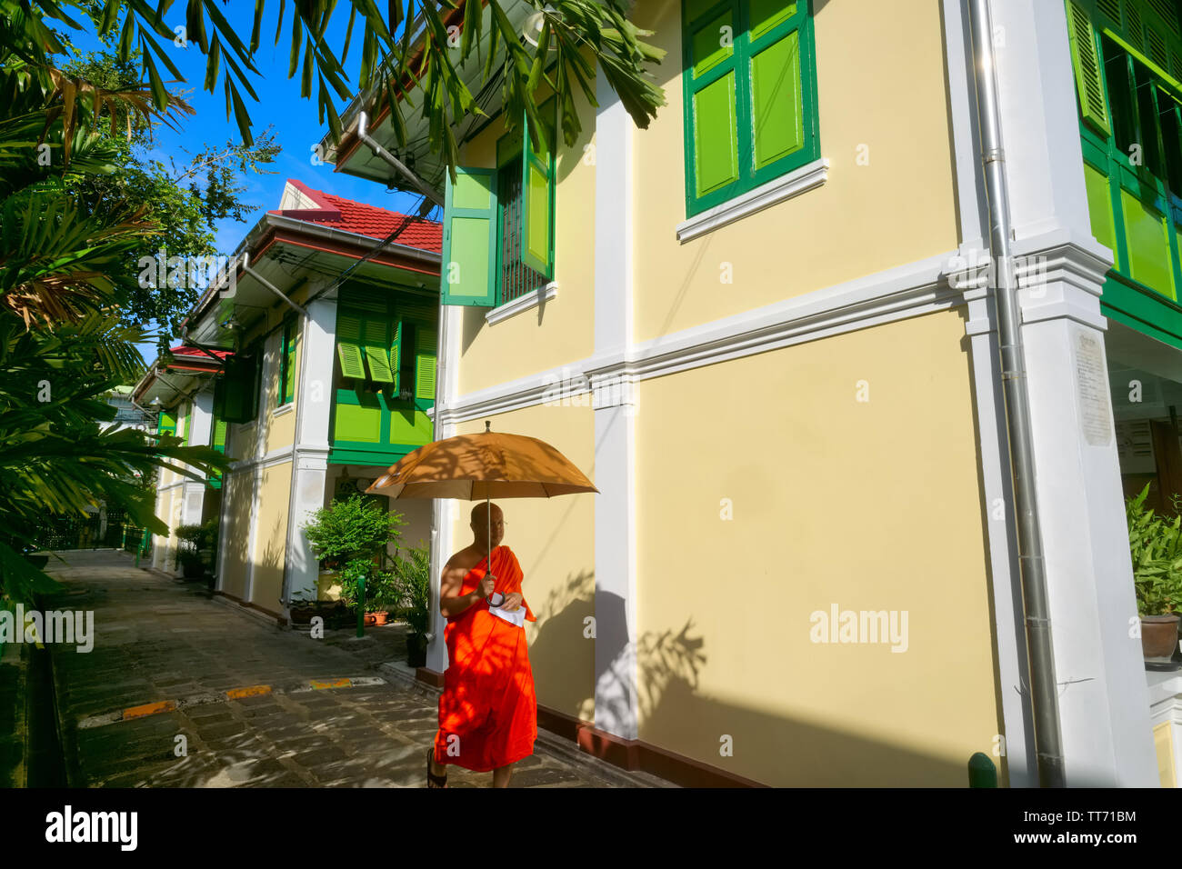 Un moine bouddhiste tenant un parapluie pour abriter du soleil passe Monk's Logements à Prague (Temple de marbre), Bangkok, Thaïlande Banque D'Images