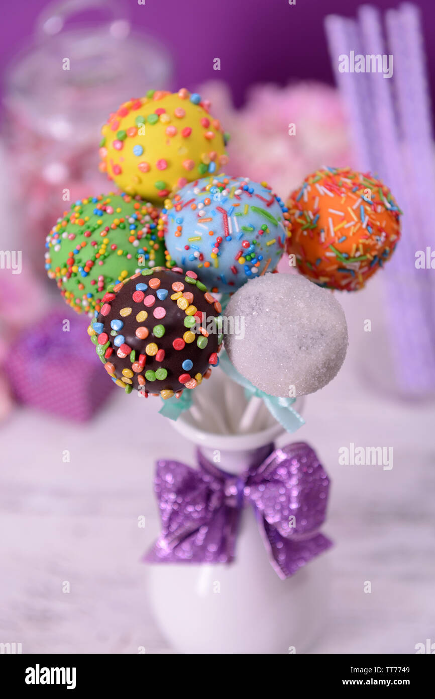 Sweet cake pops dans un vase sur la table sur fond violet Banque D'Images