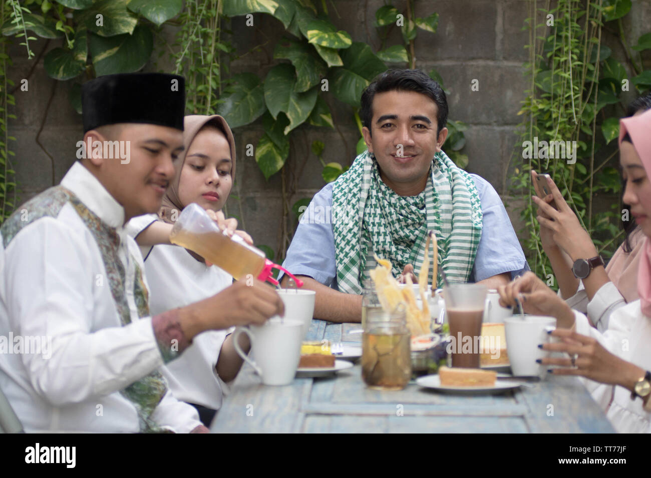 Beau sourire à l'homme musulman à l'appareil photo avec salle à manger table smiling friend célébration pendant le ramadan, le jeûne rupture Banque D'Images