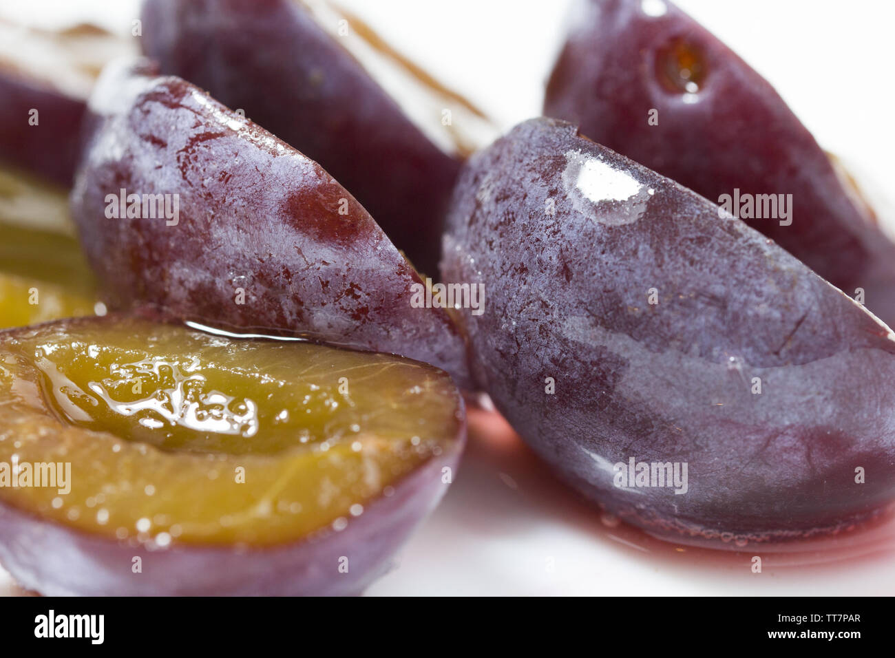 Gros plan macro de tranche de délicieux jus de prune mûre et de petits fruits congelés frais. concept Banque D'Images