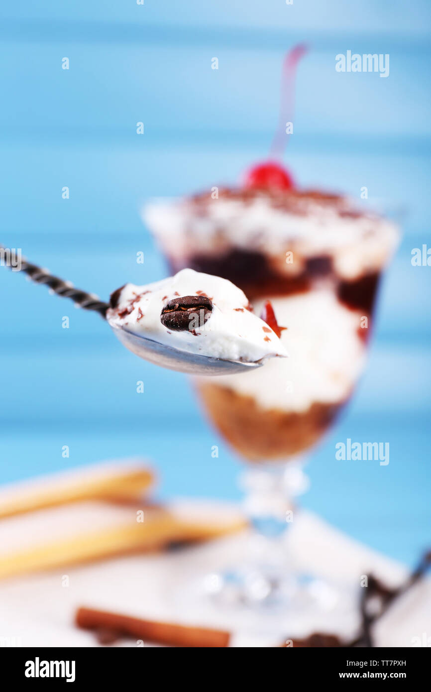 Tiramisu dessert savoureux et cuillère en verre, sur fond de bois de couleur Banque D'Images