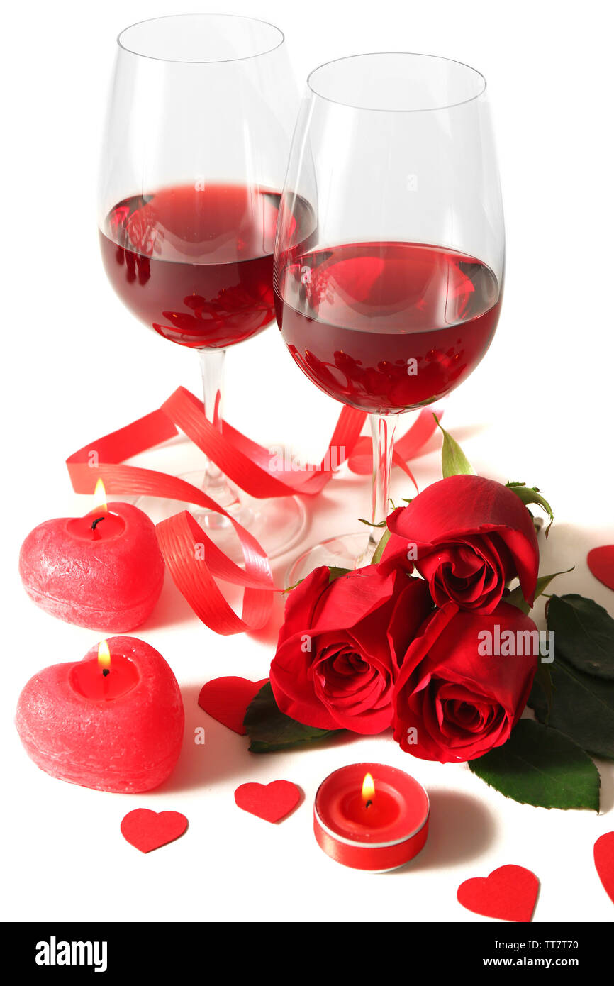 La composition avec du vin rouge dans les verres, roses rouges, du ruban et des coeurs décoratifs sur fond clair Banque D'Images