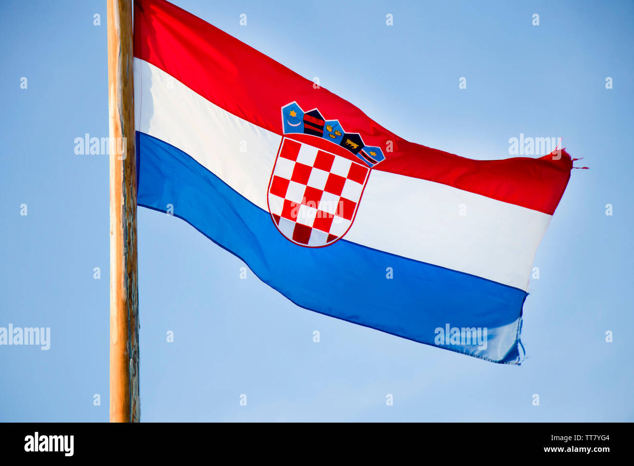 Drapeau national croate voltigeant sur poteau en bois contre le ciel bleu clair Banque D'Images